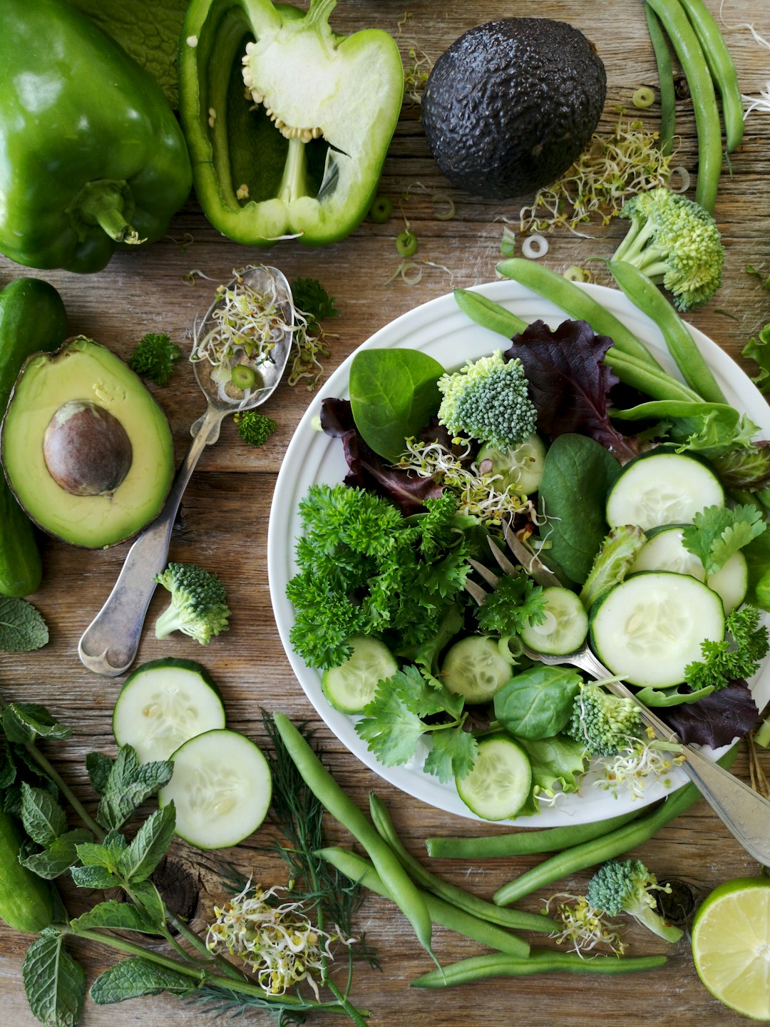 Fresh green vegetables artfully arranged on a wooden table.