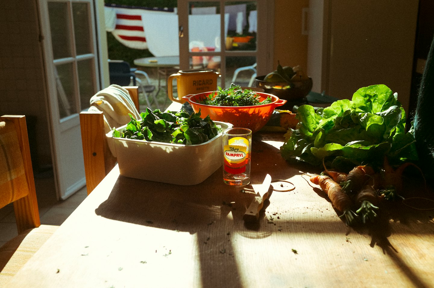 Fresh leafy vegetables and carrots on a wooden table.