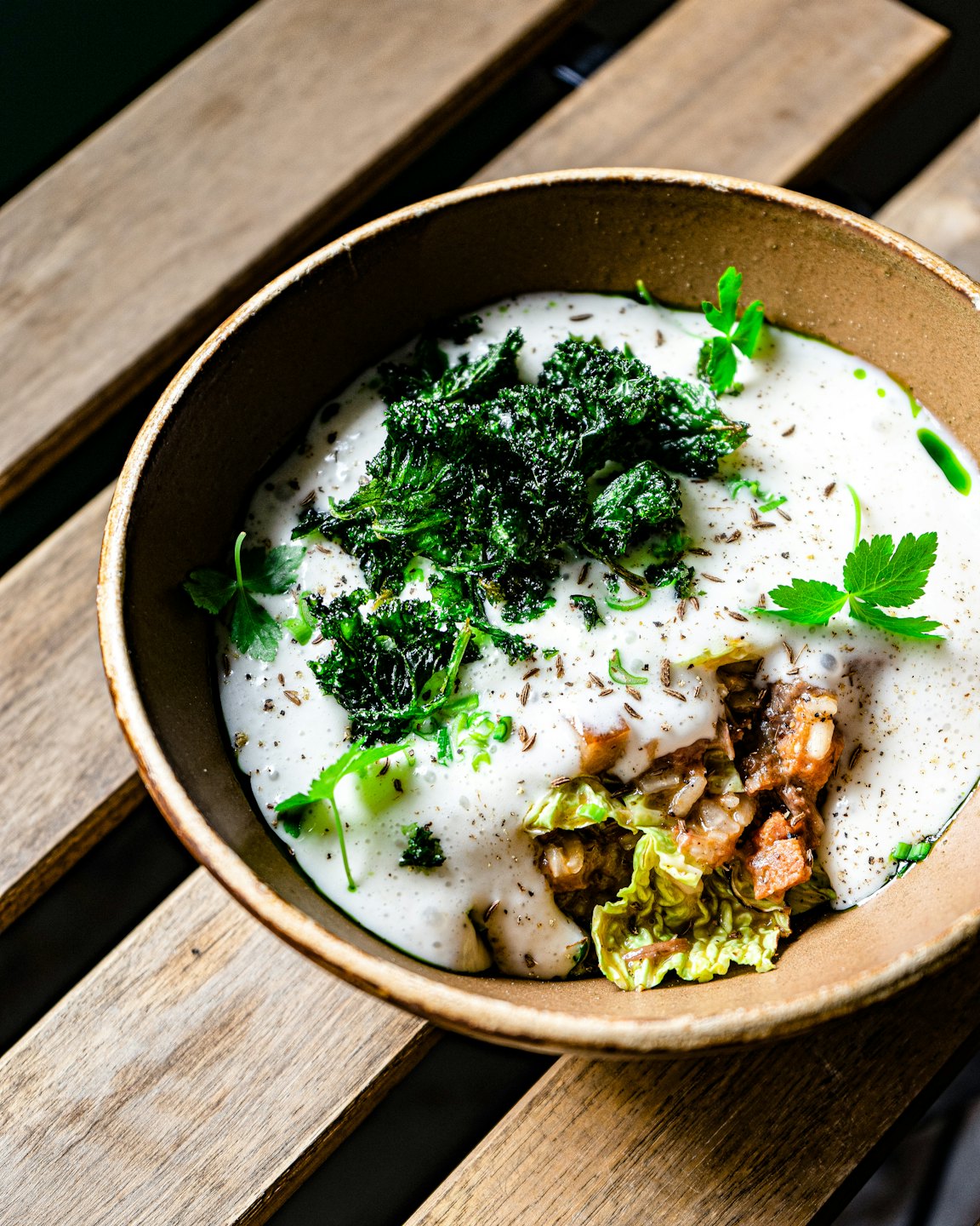 Rustic bowl filled with savory stew topped with herbs and sauce.
