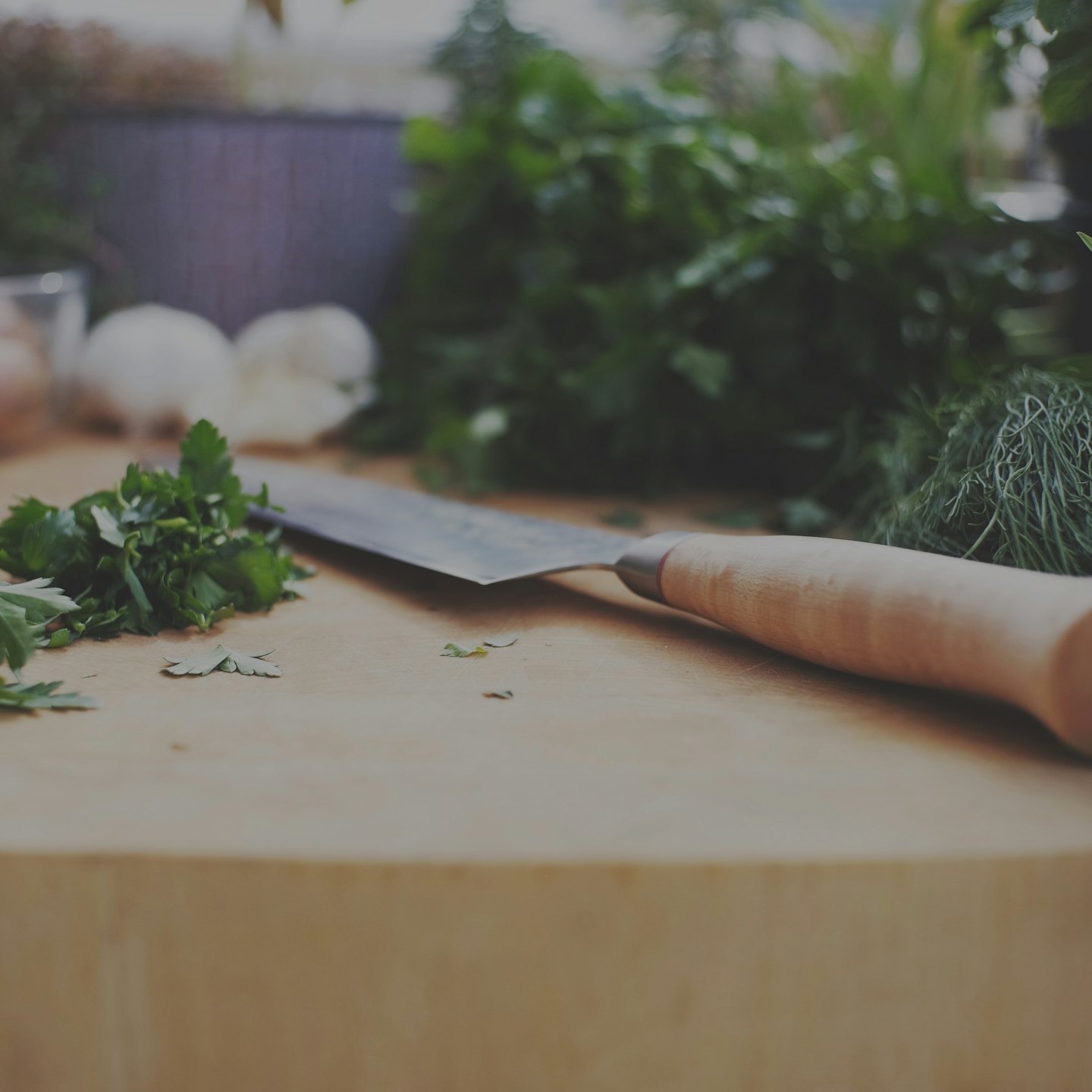 Fresh green herbs and onions chopped on a wooden board.
